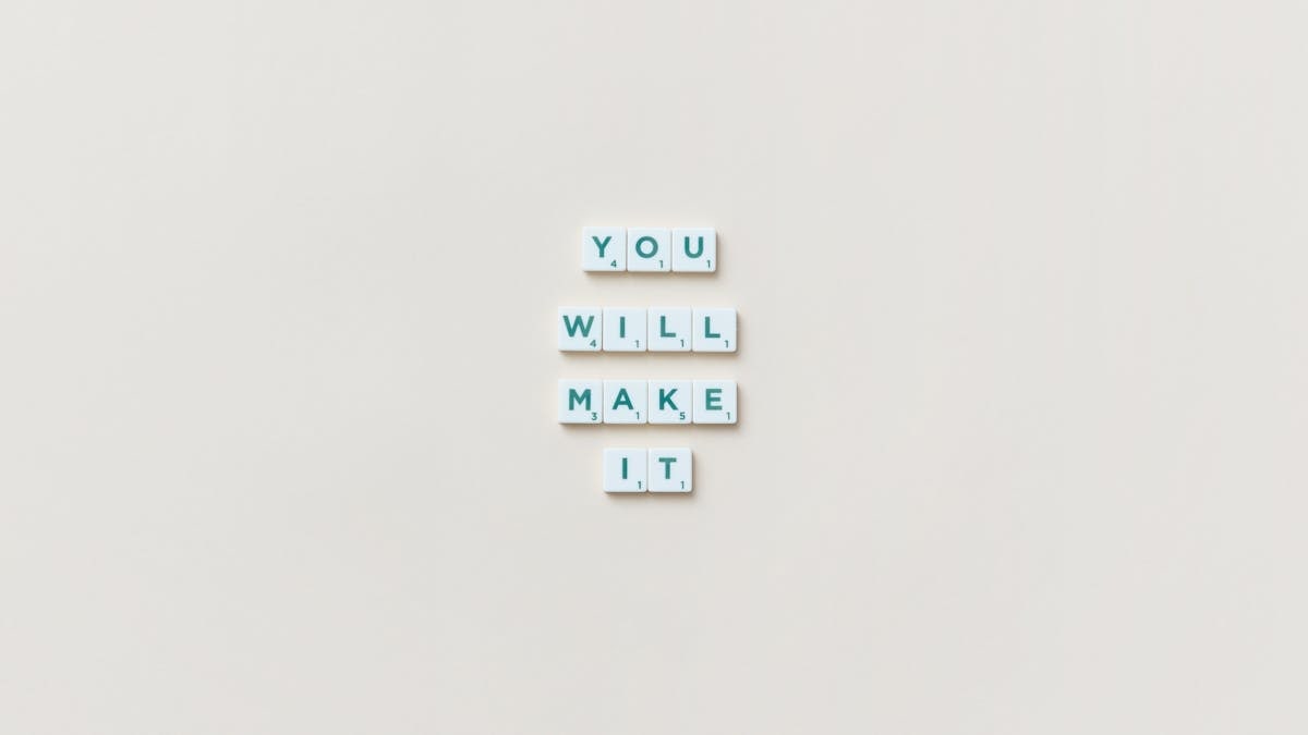 Motivational phrase 'You Will Make It' made from Scrabble tiles on a neutral background.